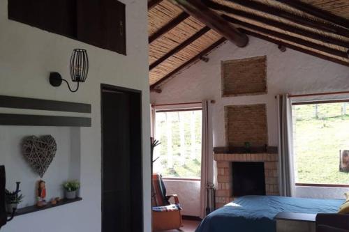 um quarto com uma cama e uma lareira em Linda mini casa campestre con Jacuzzi, chimenea... em Paipa