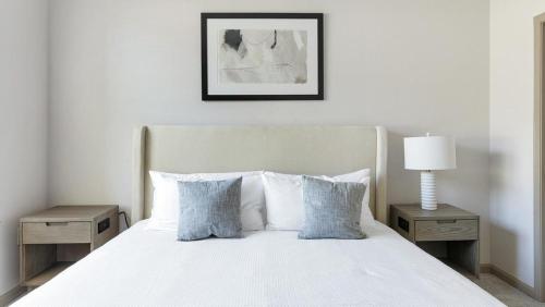 1 dormitorio con 1 cama blanca con 2 mesas y 1 lámpara en Landing Modern Apartment with Amazing Amenities (ID1230X535), en San Antonio