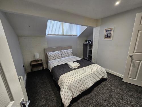 a bedroom with a bed with a black and white comforter at 4 mins walk to Haughton Dale nature reserve in Denton