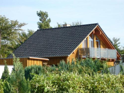 a wooden house with a black roof at Holiday home Belvedere in Alt Schwerin