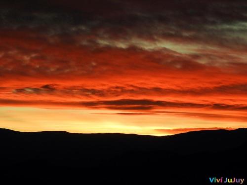 um pôr-do-sol sobre as montanhas com um vermelho em Tacita de Plata Apart em San Salvador de Jujuy