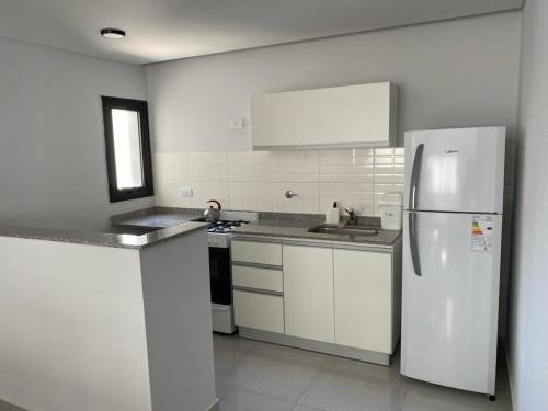 eine weiße Küche mit einem Kühlschrank und einer Spüle in der Unterkunft Hermoso dpto. Zona céntrica in Santiago del Estero