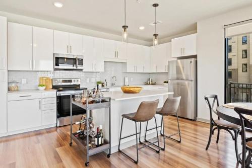 une cuisine avec des placards blancs et une table avec des chaises dans l'établissement Landing Modern Apartment with Amazing Amenities (ID6832X09), à Wilmington