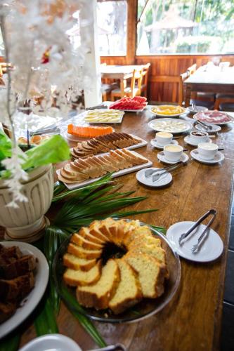 un lungo tavolo di legno sormontato da diversi tipi di cibo di Pousada Iguatiba a Paraibuna
