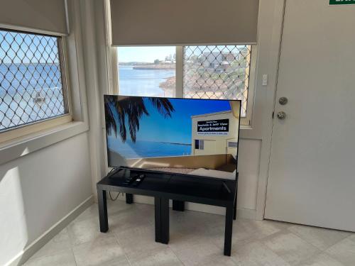 - une télévision à écran plat assise sur une table à côté d'une fenêtre dans l'établissement Beachside & Jetty View Apartment 5 - Harbour Master Apt, à Streaky Bay