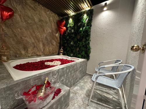 a bath tub filled with red roses next to a chair at Hotel Paris in Valledupar