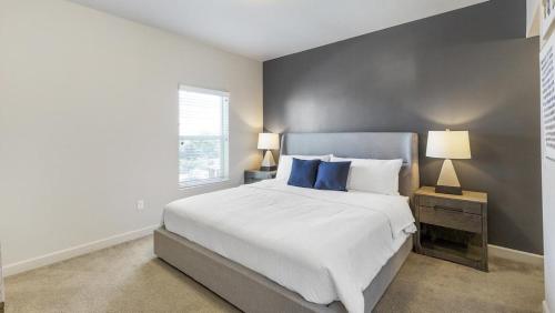 1 dormitorio con 1 cama blanca grande con almohadas azules en Landing Modern Apartment with Amazing Amenities (ID9601X99), en West Valley City