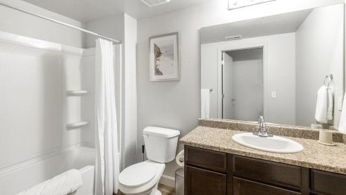 Baño blanco con aseo y lavamanos en Landing Modern Apartment with Amazing Amenities (ID9601X99), en West Valley City