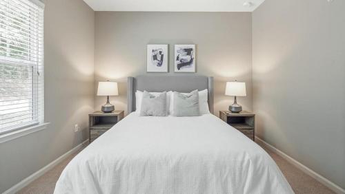 een witte slaapkamer met een groot bed met 2 lampen bij Landing Modern Apartment with Amazing Amenities (ID2796X33) in Smyrna