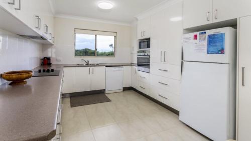 eine Küche mit weißen Schränken und einem weißen Kühlschrank in der Unterkunft Walk to Surf Beach - Ground floor apartment - Bribie Horizons Boyd St, Woorim in Woorim