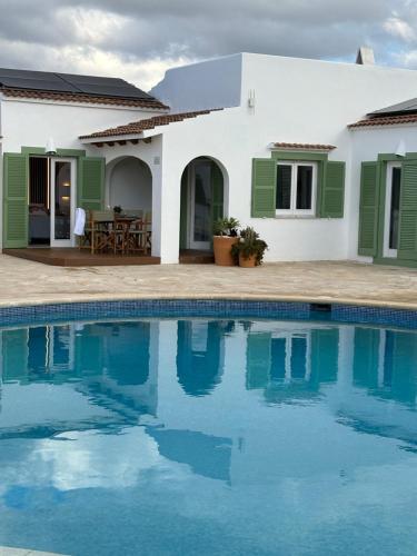 uma villa com piscina em frente a uma casa em Apartamento nº 1 Cala Blanca em Cala Blanca