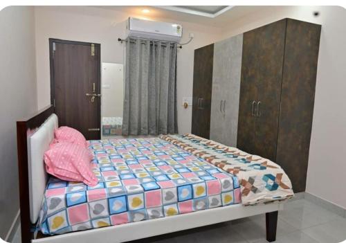 um quarto com uma cama com uma almofada cor-de-rosa em NRI NC Homestays em Tirupati