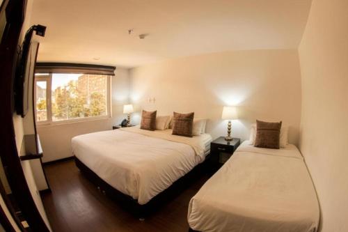 a bedroom with two beds and a window at HOTEL SHERIDAN BOGOTA in Bogotá