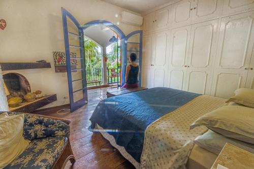 a bedroom with a bed and a woman looking out the window at Via Antiga Granja Viana in Cotia