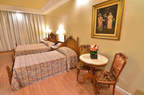 a hotel room with a bed and a table and chairs at Hotel Castelar in Sao Paulo