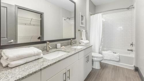 een badkamer met 2 wastafels, een bad en een toilet bij Landing Modern Apartment with Amazing Amenities (ID2101X18) in Fort Worth