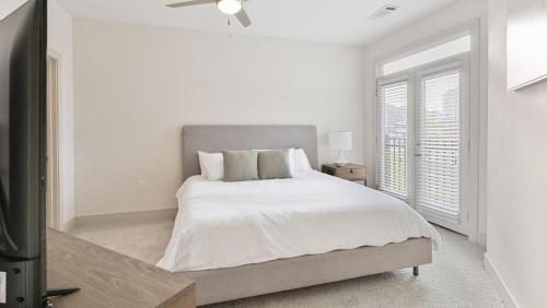 ein weißes Schlafzimmer mit einem Bett und einem Fenster in der Unterkunft Landing Modern Apartment with Amazing Amenities (ID4420X29) in Richmond