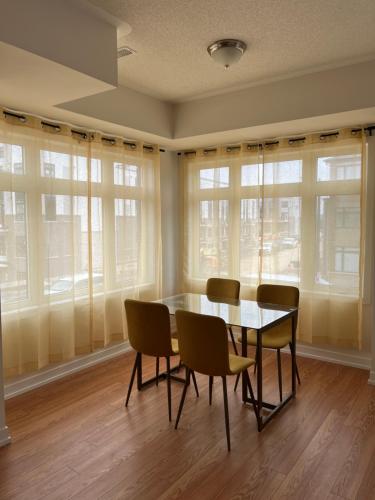 a dining room with a table and chairs and windows at Luxury Brand New Townhouse In Milton Ontario in Milton