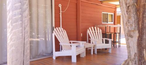 - une terrasse couverte avec 2 chaises blanches et une table dans l'établissement Desconectate, à Balneario Argentino