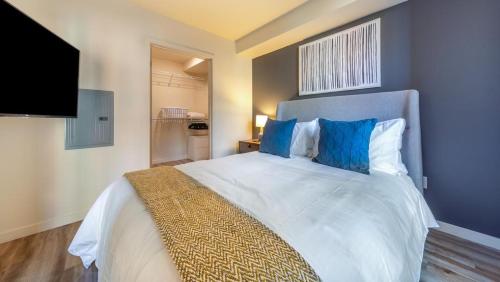 a bedroom with a large white bed with blue pillows at Landing Modern Apartment with Amazing Amenities (ID7286X92) in Tacoma