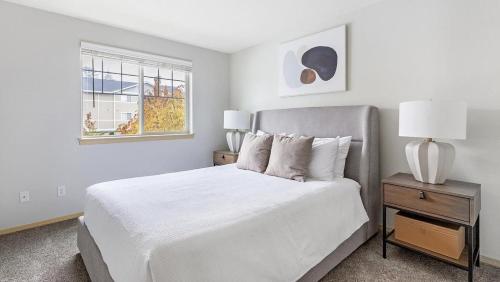 een witte slaapkamer met een bed en een raam bij Landing Modern Apartment with Amazing Amenities (ID1221X280) in Vancouver