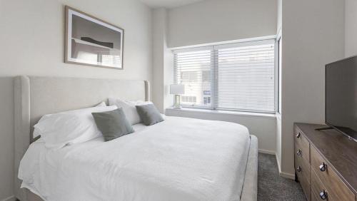 a white bedroom with a bed and a television at Landing Modern Apartment with Amazing Amenities (ID8910X05) in Omaha