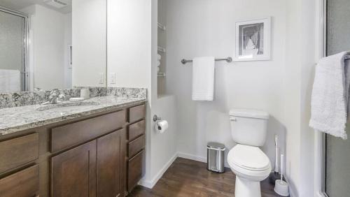 Baño blanco con aseo y lavamanos en Landing Modern Apartment with Amazing Amenities (ID8910X05) en Omaha