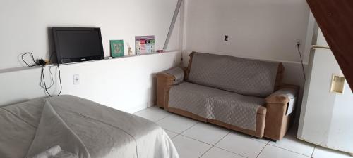 een slaapkamer met een bank en een tv aan de muur bij G.LO Loft AP 04 in Ponta Porã