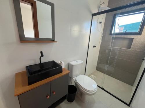 La salle de bains est pourvue de toilettes, d'un lavabo et d'une douche. dans l'établissement Temporada Praia Pinheira 2 Suítes 2 Garagens n2, à Palhoça