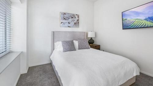 ein weißes Schlafzimmer mit einem Bett und einem Fenster in der Unterkunft Landing Modern Apartment with Amazing Amenities (ID9909X40) in Omaha