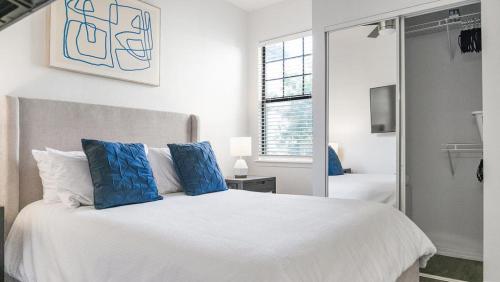 a bedroom with a large white bed with blue pillows at Landing Modern Apartment with Amazing Amenities (ID1401X027) in Tucson