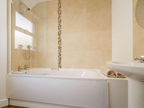 Baño blanco con bañera y lavamanos en 3 Bed in Llandudno 89331 en Llandudno