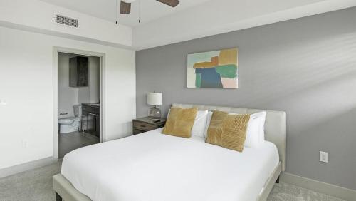 um quarto branco com uma grande cama branca com almofadas em Landing Modern Apartment with Amazing Amenities (ID1673) em Dallas