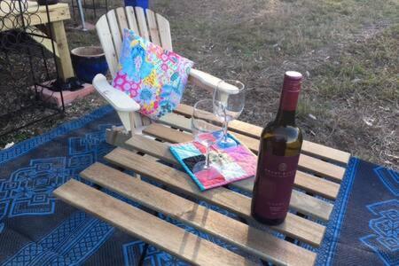 una bottiglia di vino e una borsa seduta su una panchina di White Jacaranda Tiny House a Maleny