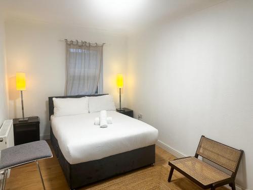 a bedroom with a white bed and a chair at Flat 1 Stay In Aldgate in London