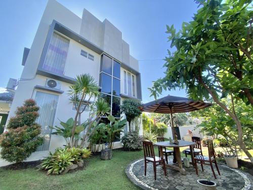a table with an umbrella in front of a house at Omah Ulfah Homestay in Banyuwangi