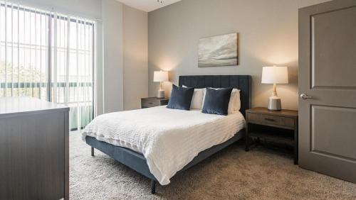 Un dormitorio con una cama con almohadas azules y una ventana en Landing Modern Apartment with Amazing Amenities (ID1988) en Houston