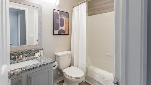 La salle de bains est pourvue de toilettes, d'un lavabo et d'un miroir. dans l'établissement Landing Modern Apartment with Amazing Amenities (ID1193X713), à Indianapolis