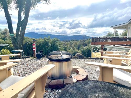 a fire pit with a grill and picnic tables at Sierra Mountain Lodge - Vacation Rentals - Yosemite in Ahwahnee