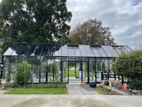 a glass greenhouse with plants in a garden at Villa Walton in Matamata