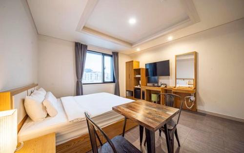 a room with a bed and a table and a desk at From H Amor Hotel Masan in Changwon