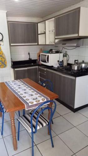 a kitchen with a table and a table and a microwave at Casa - ótima localização in Capão da Canoa