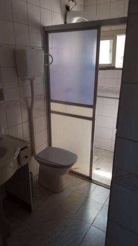 a bathroom with a toilet and a glass door at Casa - ótima localização in Capão da Canoa