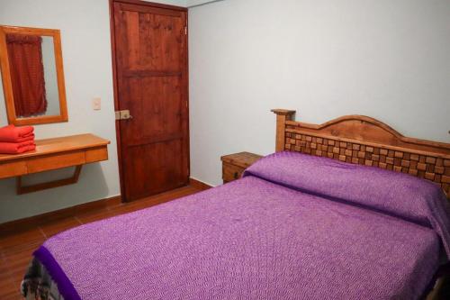 a bedroom with a purple bed with a wooden headboard at EL CAPIRO in Mineral del Chico