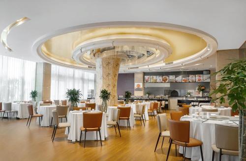 a restaurant with white tables and chairs and a large ceiling at United Kingson HoteL in Chengdu