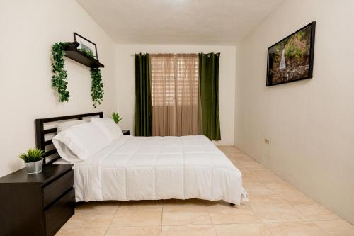 1 dormitorio con cama blanca y ventana en Casa Luquillo, en Fajardo