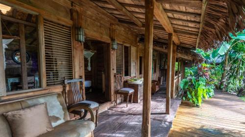 a porch of a house with a couch and chairs at Ratua Private Island Resort in Aimbuei Bay