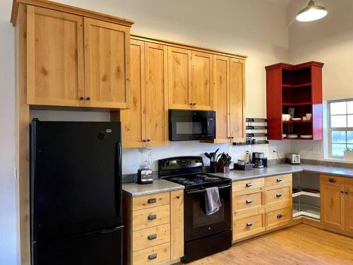 a kitchen with a black refrigerator and wooden cabinets at The Barn at Emigrant Creek in Ashland