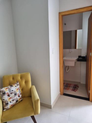 - un salon avec une chaise jaune et un lavabo dans l'établissement Villa do Aconchego apartamento super novo, à Búzios