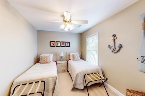 two beds in a room with a ceiling fan at The Carolina Shell in Ocean Isle Beach